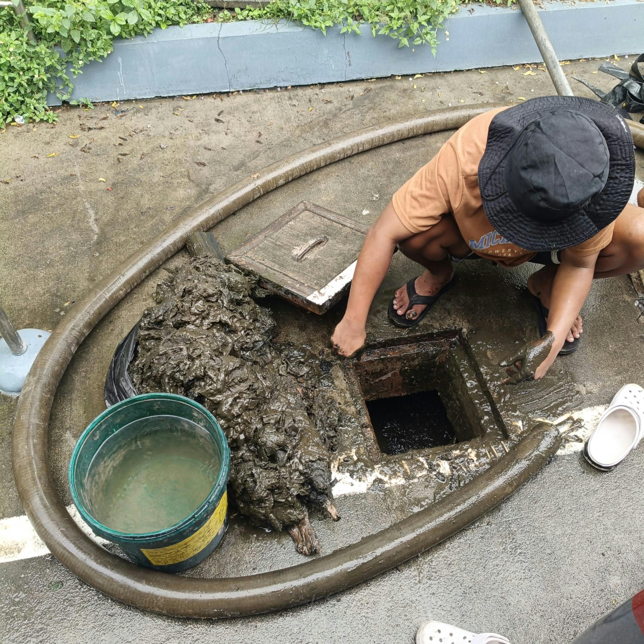 Service worker at a septic tank access opening