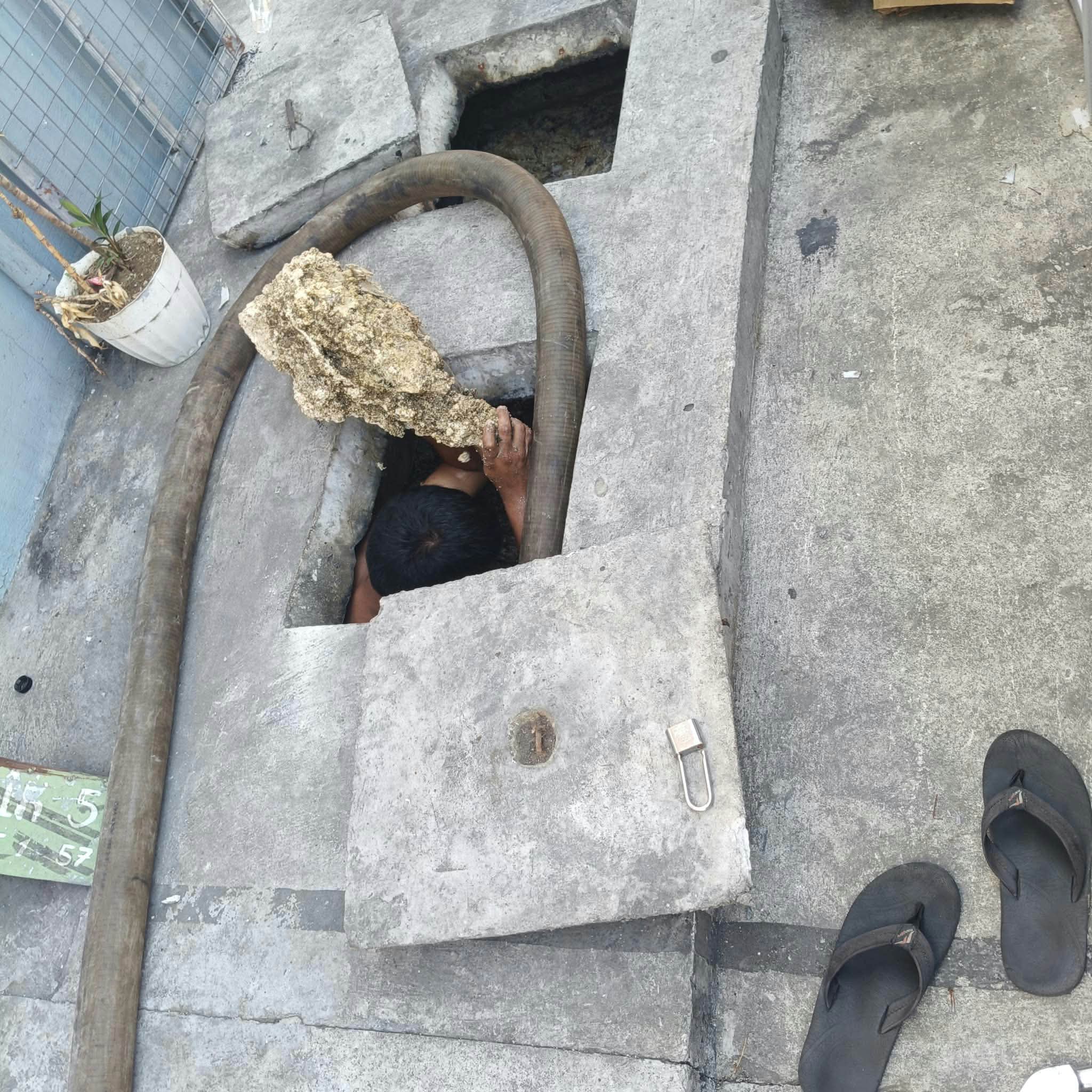 Service crew member working at an open septic tank